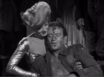 Movie still from “The Spoilers” (1942), directed by Ray Enright – An old photo of a man and a woman; Medium shot, Over the shoulder angle