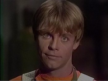 Movie still from “The Star Wars Holiday Special” (1978), directed by Steve Binder – A young man with blonde hair wearing a orange and white shirt; Close Up shot, Over the shoulder angle