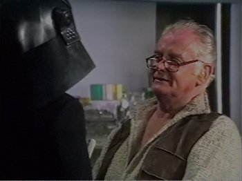 Movie still from “The Star Wars Holiday Special” (1978), directed by Steve Binder – An older man wearing glasses and a black helmet; Close Up shot, Over the shoulder angle
