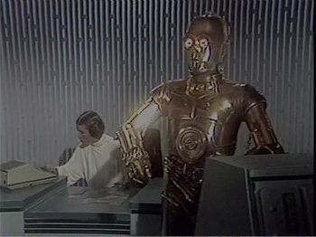 Movie still from “The Star Wars Holiday Special” (1978), directed by Steve Binder – An image of a man sitting at a computer desk with a c - 3 po; Wide shot, Low angle