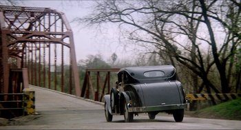 Movie still from “The Stunt Man” (1980), directed by Richard Rush – An old car is driving down the street; Wide shot, High angle
