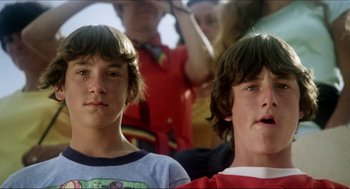 Movie still from “The Stunt Man” (1980), directed by Richard Rush – Two young men are sitting in front of a group of people; Close Up shot, Low angle