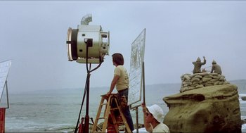 Movie still from “The Stunt Man” (1980), directed by Richard Rush – A man standing on top of a ladder next to an easel; Wide shot, Low angle