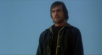 Movie still from “The Stunt Man” (1980), directed by Richard Rush – A man with long hair wearing a black shirt and jacket; Close Up shot, Low angle