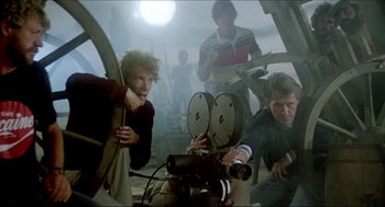 Movie still from “The Stunt Man” (1980), directed by Richard Rush – A group of people standing next to each other in a room; Medium shot, Low angle