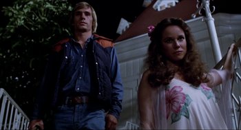 Movie still from “The Stunt Man” (1980), directed by Richard Rush – A man and a woman standing next to each other in front of a house; Medium shot, Low angle