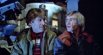 Movie still from “The Stunt Man” (1980), directed by Richard Rush – Two men sitting next to each other on a bus; Medium shot, Low angle