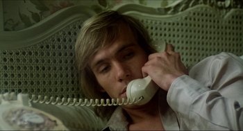 Movie still from “The Stunt Man” (1980), directed by Richard Rush – A man talking on a phone while sitting on a couch; Close Up shot, Low angle