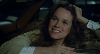 Movie still from “The Stunt Man” (1980), directed by Richard Rush – A woman smiling for the camera while sitting on a couch; Close Up shot, Low angle