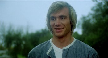 Movie still from “The Stunt Man” (1980), directed by Richard Rush – A man with long blonde hair smiling for the camera; Close Up shot, Low angle