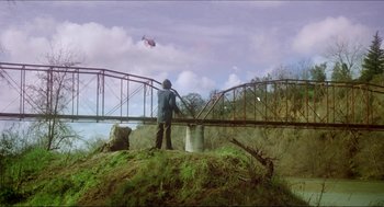 Movie still from “The Stunt Man” (1980), directed by Richard Rush – A man standing on top of a hill next to a bridge; Extreme Wide shot, Low angle