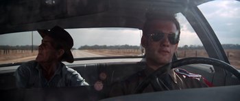 Movie still from “The Sugarland Express” (1974), directed by Steven Spielberg – A man driving a car on a road; Close Up shot, Low angle