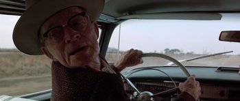 Movie still from “The Sugarland Express” (1974), directed by Steven Spielberg – An old man driving a car in the road; Close Up shot, Over the shoulder angle