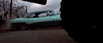 Movie still from “The Sugarland Express” (1974), directed by Steven Spielberg – A car driving down a street next to a building; Wide shot, Low angle