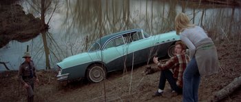 Movie still from “The Sugarland Express” (1974), directed by Steven Spielberg – An old blue car in the middle of the woods; Wide shot, High angle