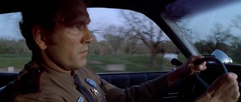 Movie still from “The Sugarland Express” (1974), directed by Steven Spielberg – A man in a police uniform driving a car; Close Up shot, Low angle