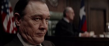 Movie still from “The Sugarland Express” (1974), directed by Steven Spielberg – A man in a suit and tie sitting in a courtroom; Close Up shot, Over the shoulder angle