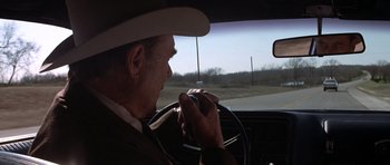 Movie still from “The Sugarland Express” (1974), directed by Steven Spielberg – An older man in a cowboy hat driving a car; Close Up shot, Over the shoulder angle