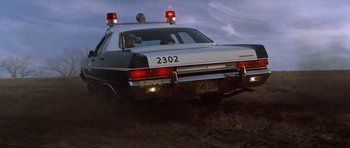 Movie still from “The Sugarland Express” (1974), directed by Steven Spielberg – A police car driving down a dirt road; Wide shot, Low angle