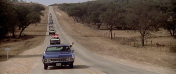 Movie still from “The Sugarland Express” (1974), directed by Steven Spielberg – A long line of cars driving down a road; Extreme Wide shot, Low angle