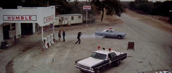 Movie still from “The Sugarland Express” (1974), directed by Steven Spielberg – A police car and a cop car on a street; Wide shot, High angle