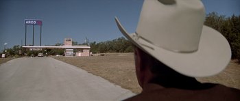 Movie still from “The Sugarland Express” (1974), directed by Steven Spielberg – A man wearing a cowboy hat looking out over a field; Extreme Wide shot, Over the shoulder angle
