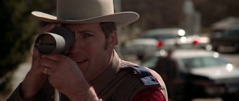 Movie still from “The Sugarland Express” (1974), directed by Steven Spielberg – A man in a uniform talking on a cell phone; Close Up shot, Over the shoulder angle