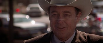 Movie still from “The Sugarland Express” (1974), directed by Steven Spielberg – An older man wearing a cowboy hat in front of a car; Close Up shot, Over the shoulder angle