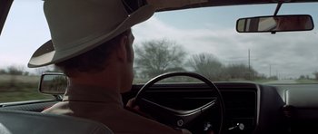Movie still from “The Sugarland Express” (1974), directed by Steven Spielberg – A man in a hat is driving a car; Close Up shot, Low angle