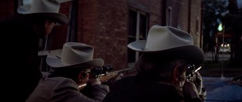 Movie still from “The Sugarland Express” (1974), directed by Steven Spielberg – Two men in hats are holding guns and looking at a building; Close Up shot, Over the shoulder angle