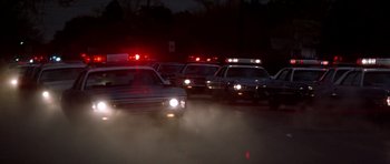 Movie still from “The Sugarland Express” (1974), directed by Steven Spielberg – A line of police cars driving down a street at night; Wide shot, High angle