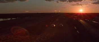 Movie still from “The Sugarland Express” (1974), directed by Steven Spielberg – Two cars driving down a road at sunset; Extreme Wide shot, High angle