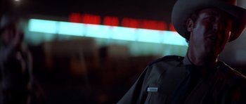 Movie still from “The Sugarland Express” (1974), directed by Steven Spielberg – A person wearing a black jacket standing in front of a neon sign; Close Up shot, Low angle