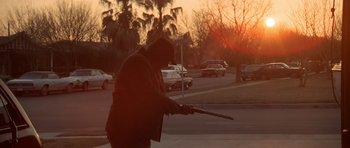 Movie still from “The Sugarland Express” (1974), directed by Steven Spielberg – A man holding a gun while standing on the side of a road; Wide shot, Low angle