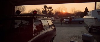 Movie still from “The Sugarland Express” (1974), directed by Steven Spielberg – The sun is setting over a parking lot with cars parked; Wide shot, Low angle