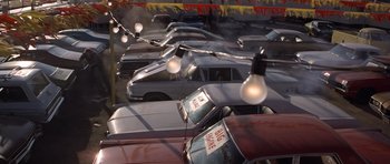 Movie still from “The Sugarland Express” (1974), directed by Steven Spielberg – A bunch of cars that are parked in a parking lot; Extreme Wide shot, High angle