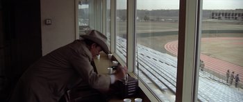 Movie still from “The Sugarland Express” (1974), directed by Steven Spielberg – A man sitting at a table in front of a large window; Wide shot, High angle