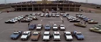 Movie still from “The Sugarland Express” (1974), directed by Steven Spielberg – A parking lot filled with lots of parked cars; Extreme Wide shot, High angle
