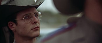 Movie still from “The Sugarland Express” (1974), directed by Steven Spielberg – A person wearing glasses and a hat; Close Up shot, Over the shoulder angle