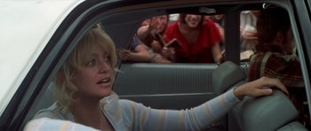 Movie still from “The Sugarland Express” (1974), directed by Steven Spielberg – A group of people in the back of a car; Medium shot, Over the shoulder angle