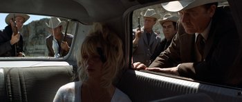 Movie still from “The Sugarland Express” (1974), directed by Steven Spielberg – A woman sitting in the back of a car with two men in the back; Medium shot, Over the shoulder angle