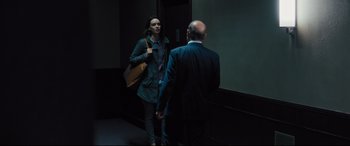 Movie still from “The Super” (2017), directed by Stephan Rick – A man and a woman standing next to each other in front of an elevator; Medium shot, Over the shoulder angle