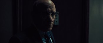 Movie still from “The Super” (2017), directed by Stephan Rick – An older man wearing glasses and a suit; Close Up shot, Low angle