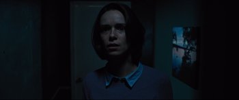 Movie still from “The Super” (2017), directed by Stephan Rick – A woman standing in a dark room with her head turned to one side; Close Up shot, Over the shoulder angle