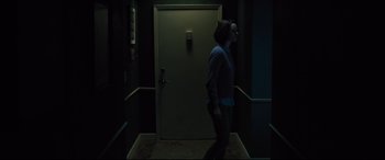 Movie still from “The Super” (2017), directed by Stephan Rick – A woman is walking in a dark hallway; Wide shot, Low angle