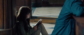Movie still from “The Super” (2017), directed by Stephan Rick – A woman sitting on the ground reading a book; Medium shot, High angle