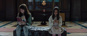 Movie still from “The Super” (2017), directed by Stephan Rick – A young girl sitting next to a woman in a room; Medium shot, High angle