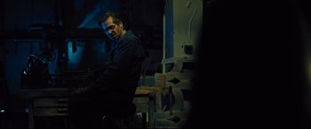 Movie still from “The Super” (2017), directed by Stephan Rick – A man sitting in a chair in a room; Medium shot, Over the shoulder angle