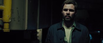 Movie still from “The Super” (2017), directed by Stephan Rick – A man with a beard is standing in a dark room; Close Up shot, Low angle