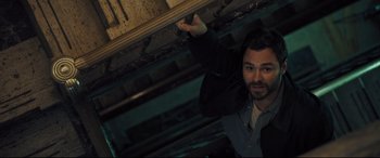 Movie still from “The Super” (2017), directed by Stephan Rick – A man standing in a dark room holding something up; Medium shot, Overhead angle